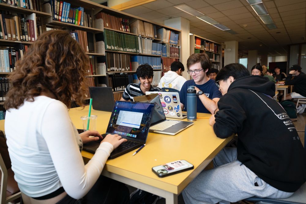 Image of four students working in a library