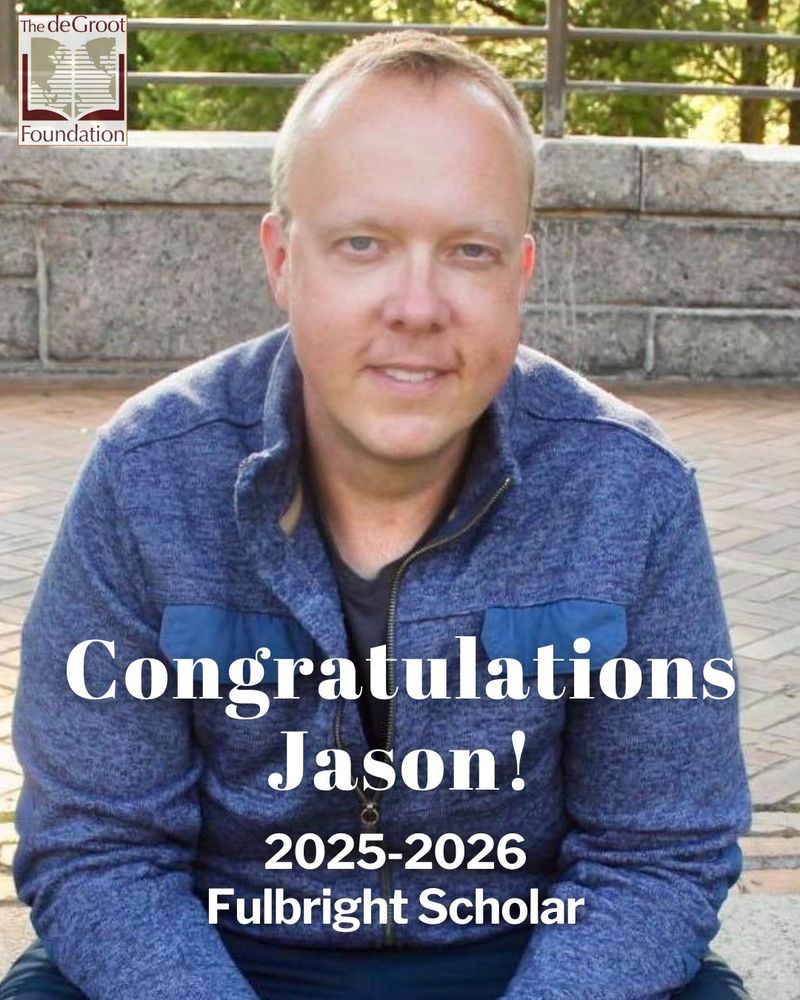 Headshot of writer Jason Prokowiew smiling at the camera in a blue jacket in front of a stone background. The de Groot Foundation open book logo is in the top left corner. White text under Jason's face reads "Congratulations Jason!" in larger text and "2025-2026 Fulbright Scholar" in smaller text underneath.