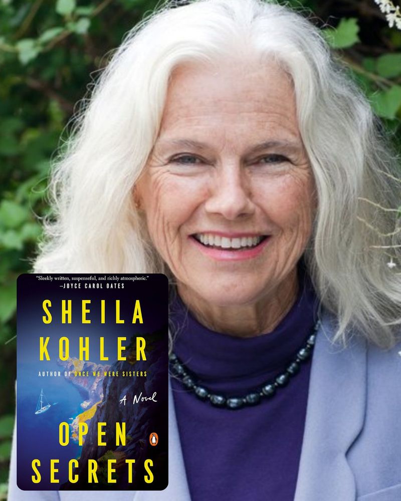 Headshot of author Sheila Kohler smiling at the camera with long white hair, a beaded necklace, and purple top. Her book cover, OPEN SECRETS, is in the bottom left corner. Th cover shows an image of a cliff, beach, and sailboat in the ocean, with "SHEILA KOHLER, Author of When We Were Sisters" and OPEN SECRETS in large yellow letters.