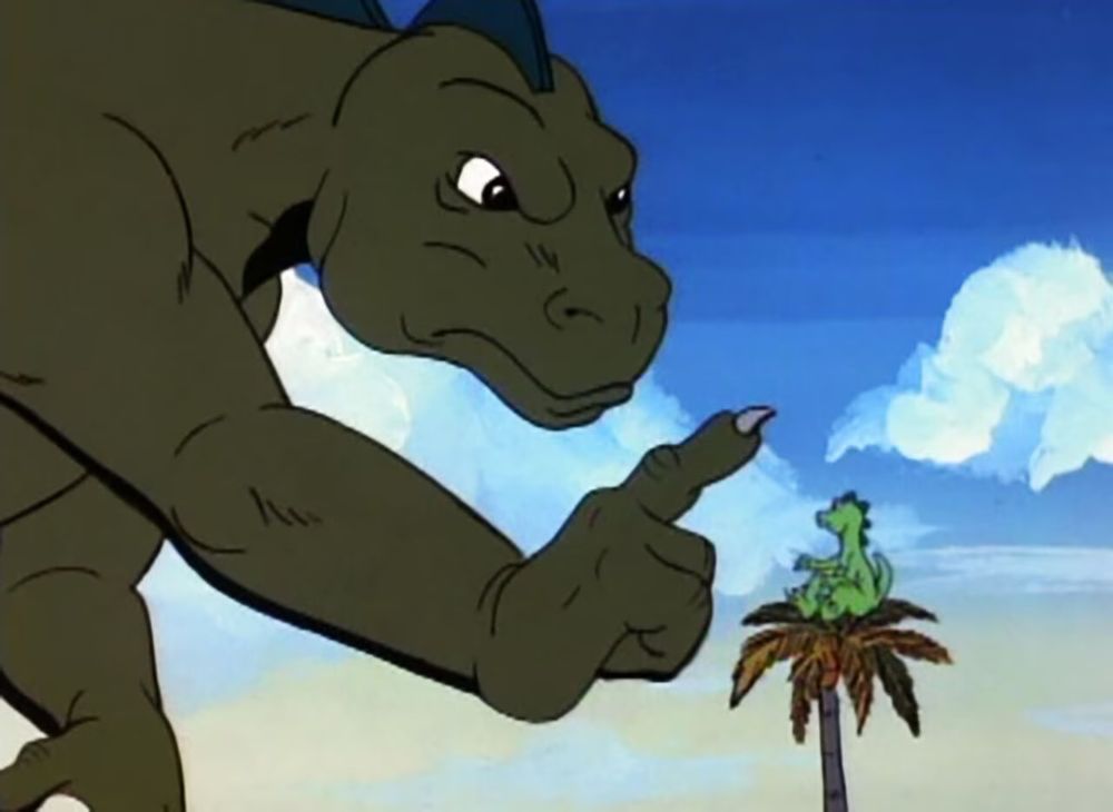 Godzilla leans over at the small godzooky who is siting in a palm tree and shakes his finger. Godzilla is proper cross!!! 