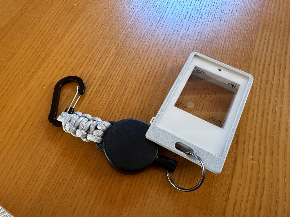 カード型のトイカメラinstantsnapに、3dプリンタ製のケースをつけている。下部にストラップを通せる穴があいていて、リール型のカラビナをつけている。