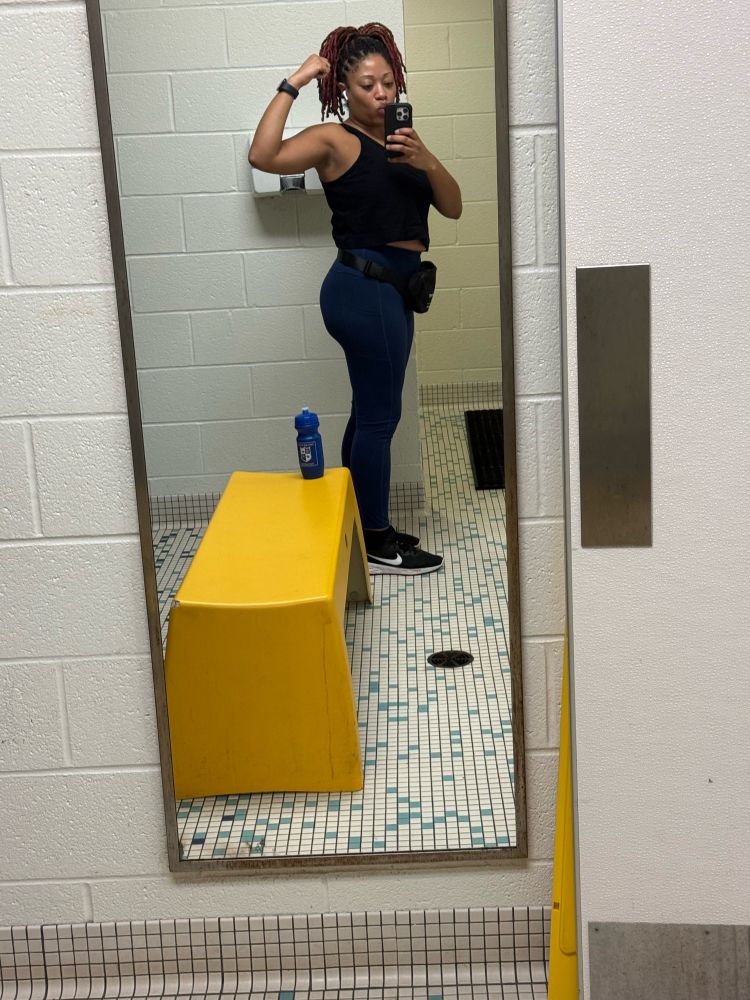 A light skinned Black girl with locs taking a gym side mirror selfie to show the arm progress 