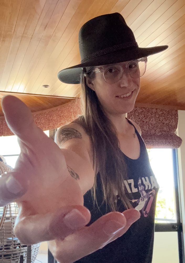 a woman wearing a hat reaching toward the camera