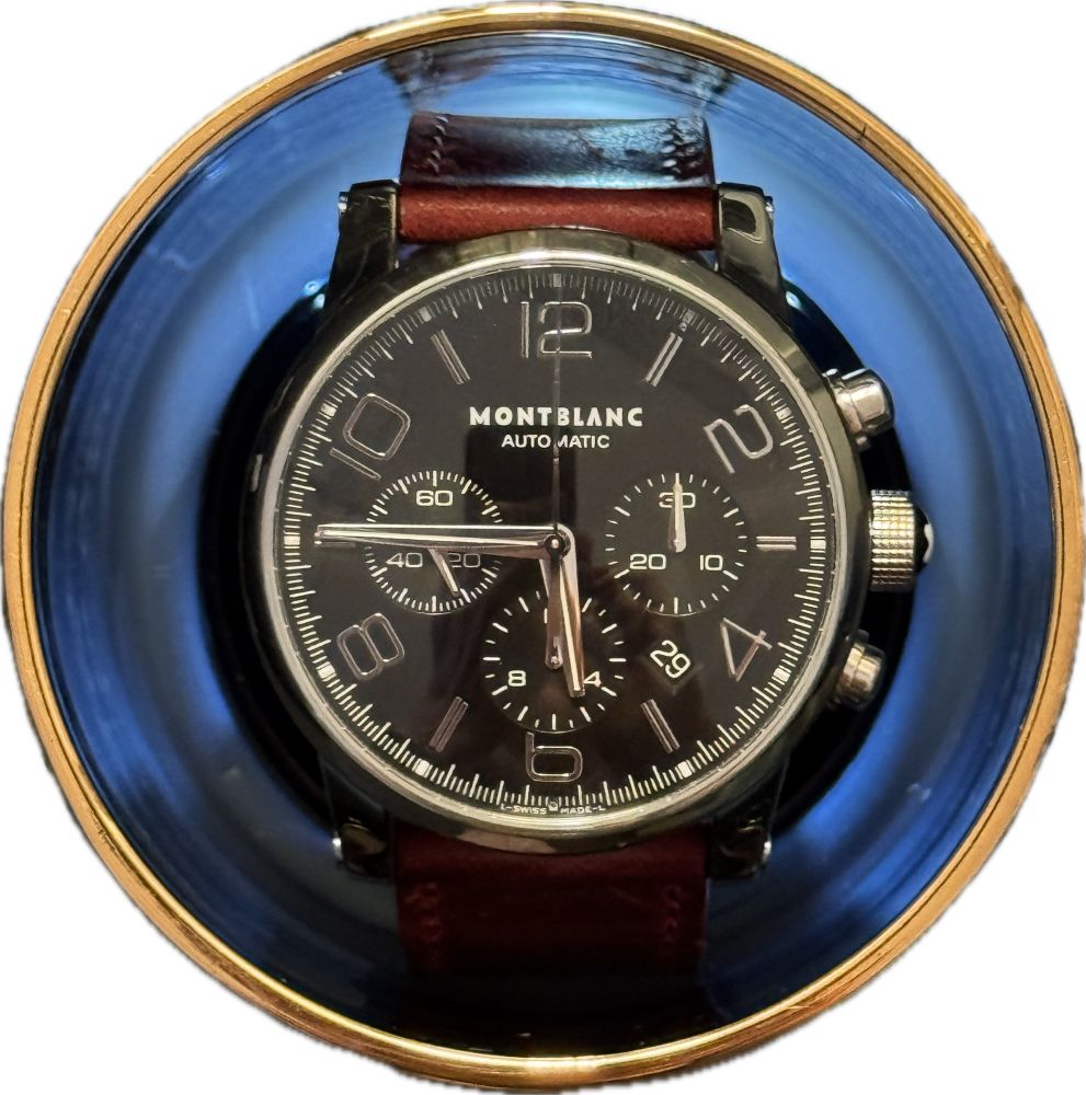 a montblanc watch with a burgundy band in an illuminated blue glass with gold rim