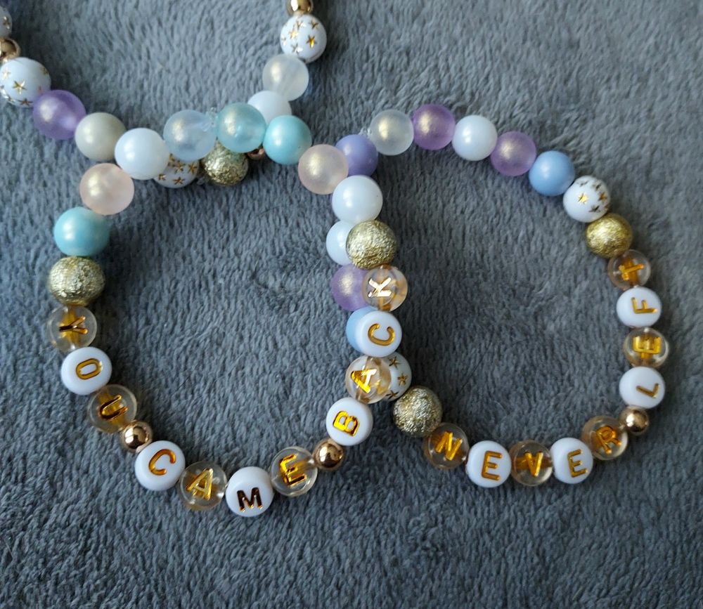 Three stretch bracelets with pearly plastic beads. One has a gold and aqua color scheme and says YOU CAME BACK. Another has a gold and purple color scheme and says NEVER LEFT.