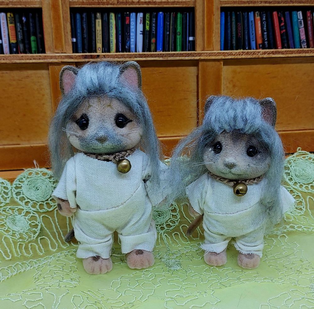 Two Calico Critters/Sylvanian Familes cat figures customized to look like Ed Teach from "Our Flag Means Death." One figure is slightly taller. Both have gray yarn hair, collars with small gold bells, and sack onesies.