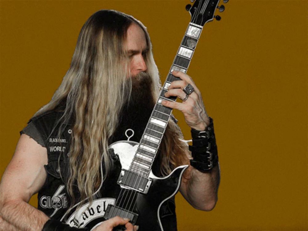 a man with long blonde hair and a beard is playing a guitar with a label on it