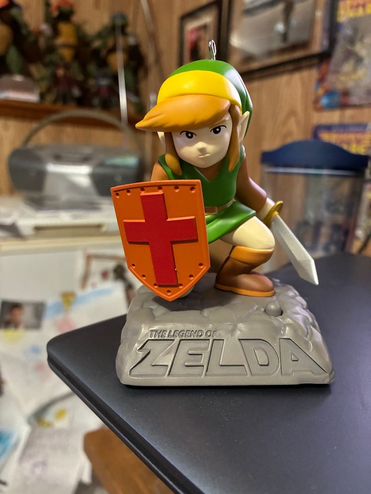 Hallmark The Legend of Zelda Christmas ornament featuring Link crouched with his orange, cross-emblem, shield and sword drawn. Inspired by the artwork from the original game.