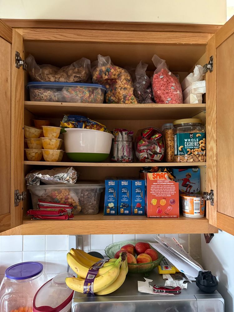 Top shelf 6 types of cereal, saltines
Middle shelf fruit cups bevita cookie packs organic fruit twists strawberry wafer bars goldfish cashews 
Bottom shelf more cereal nitro grain bars I’m 3 flavors fruit snacks z bars 
Microwave shelf has apples and bananas 