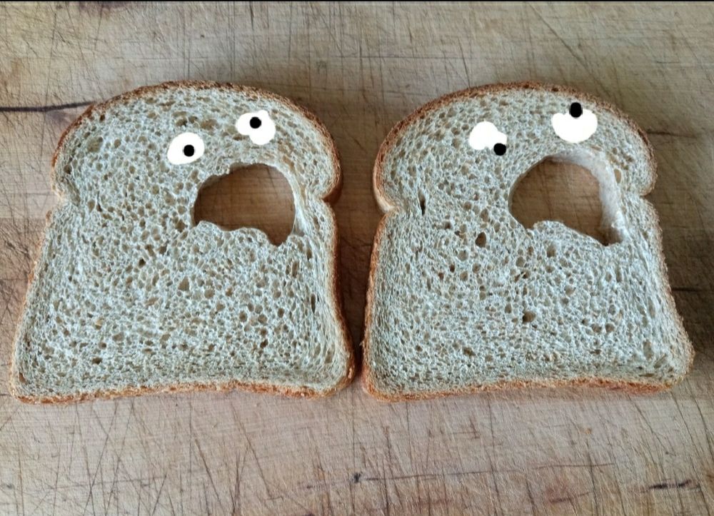 Two pieces of bread with amorphous holes in them to which MSPaint style googly eyes have been added, making Slice of Bread Monsters
