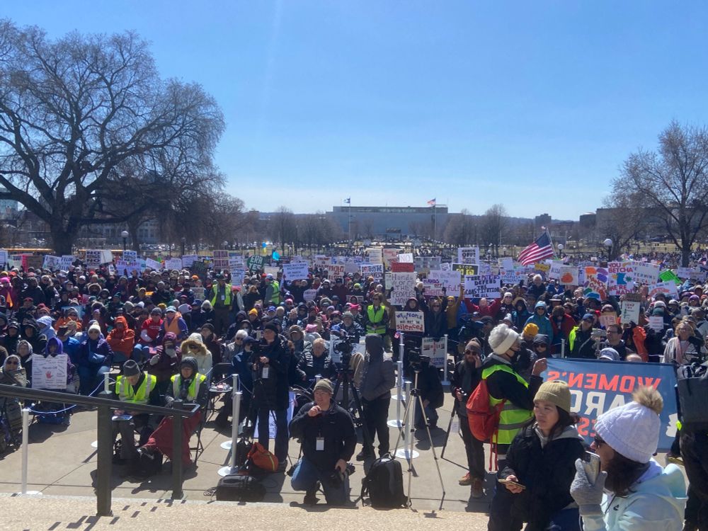 Crowd of thousands with signs on front lawn of the Minnesota State Capitol. 
