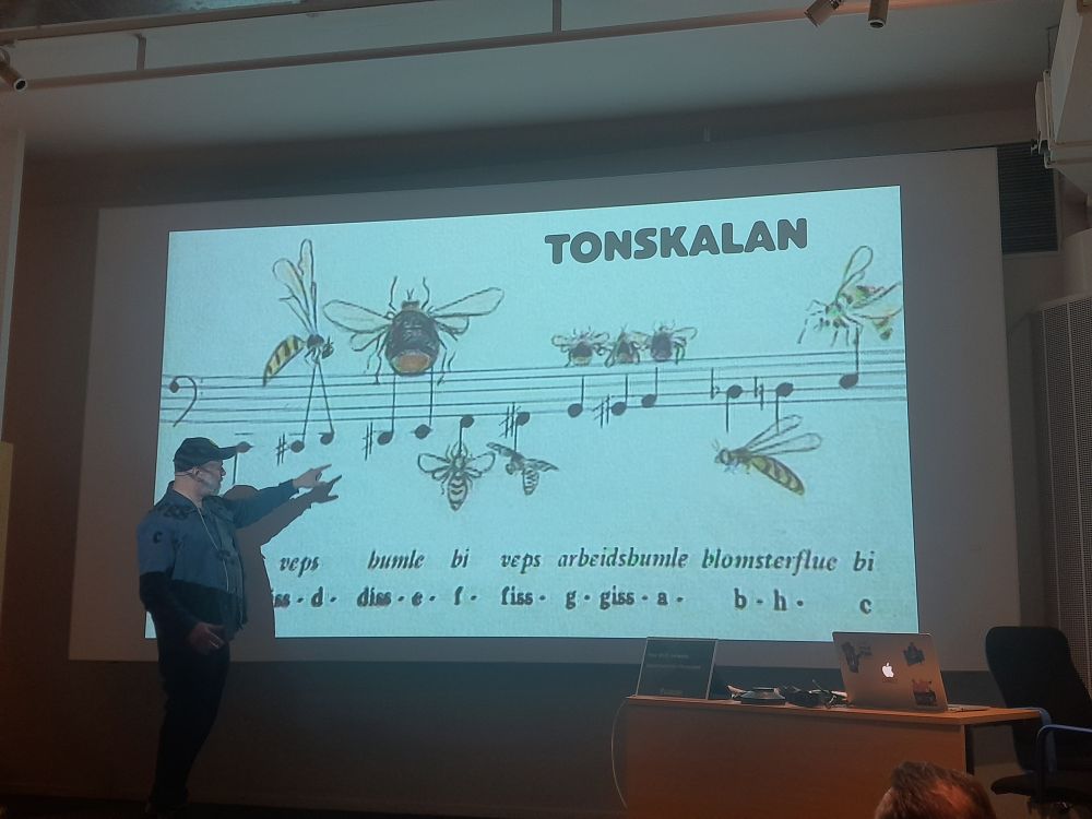 Tommie Jönsson shows us how Gaby Stenberg organized the different buzz she'd recorded into a tonal scale. He's pointing at a delightful illustration of a song where different insects are flying around the notes.