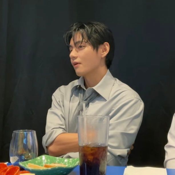 tae wearing a shirt and loose tie combo with his sleeves rolled up. 