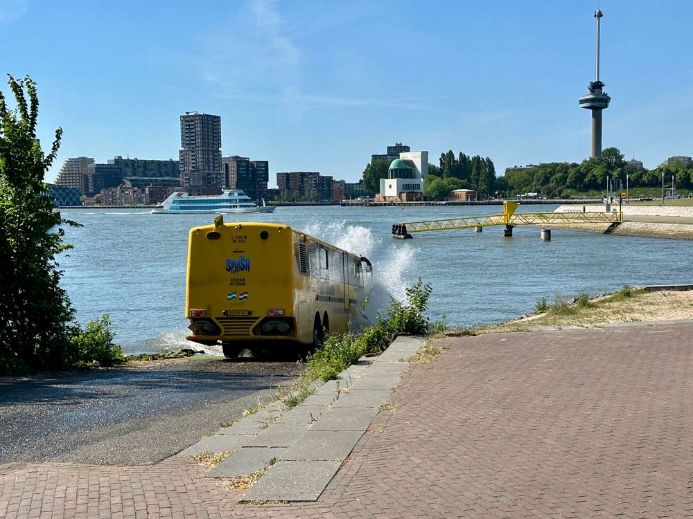 A yellow bus drives into a river 