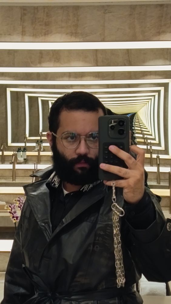 Eu, usando capa de chuva, na frente de um corredor de espelhoz