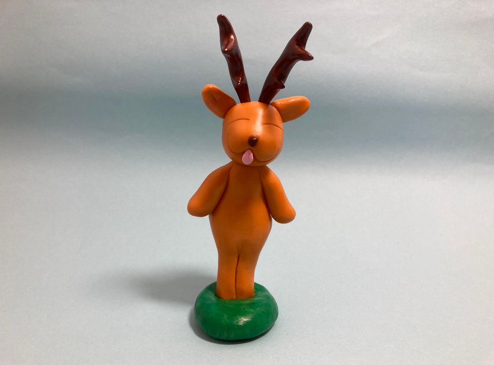 Lupin, the anthropomorphic deer boy playfully sticking his tongue out at the viewer, while standing on a blue background 