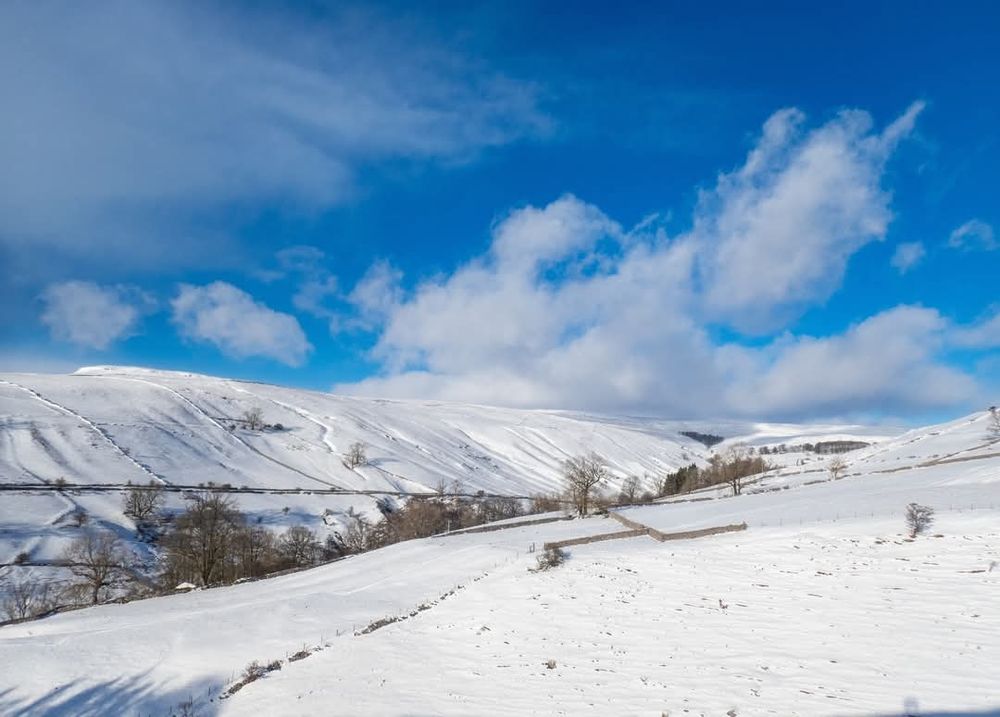 A snow covered valley and hillsides under a blue sky