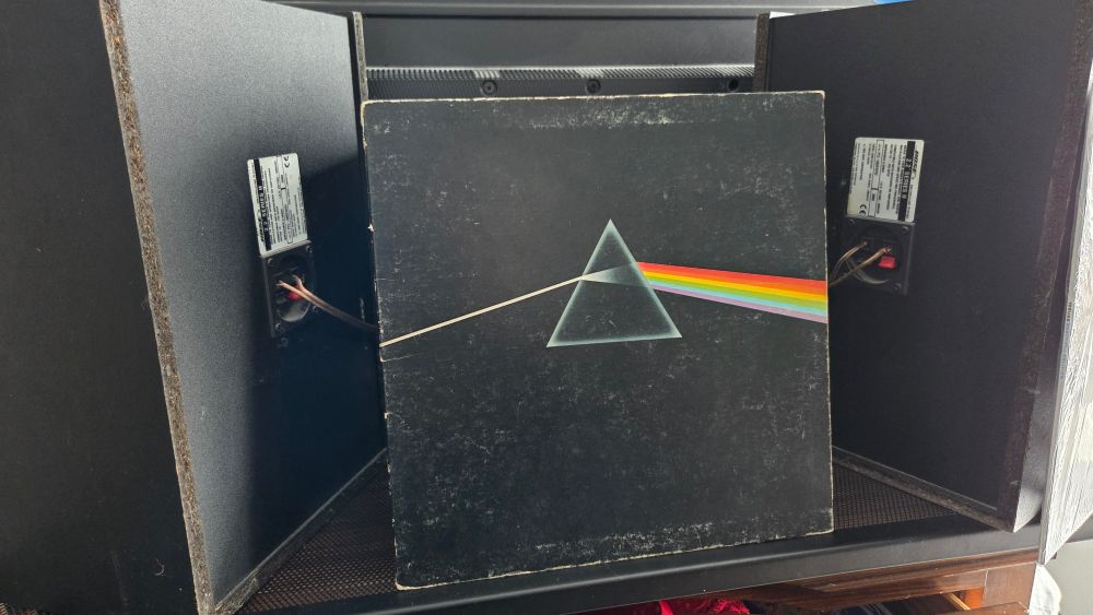 Vinyl record of Pink Floyd's Dark Side of the Moon. 2 vintage Bose speakers on each side of the vinyl 