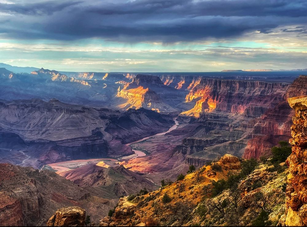 A colorful canyon at sunset with a river snaking through the bottom. 