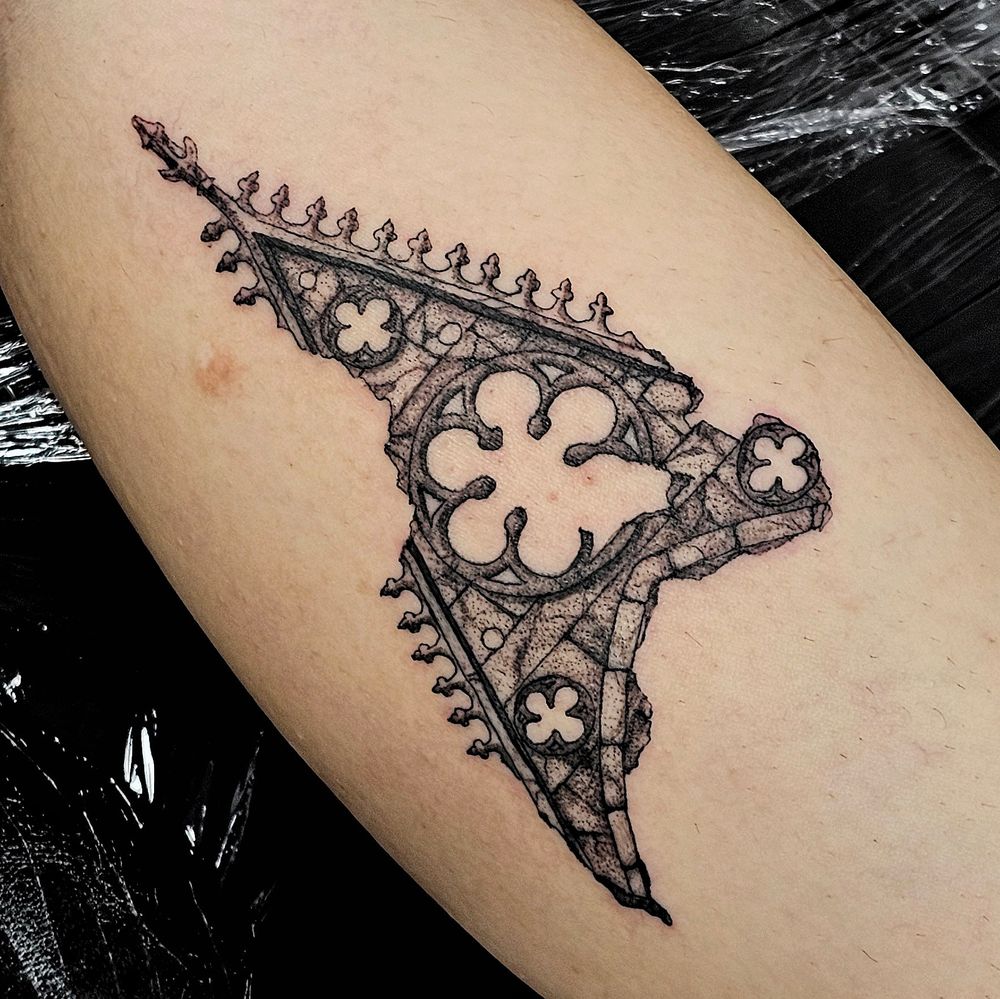 Medieval church ruin tattoo, of a spire with rose window and chunks missing in illustrative style 