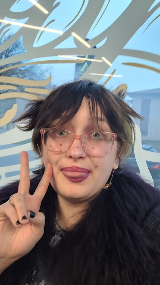 Selfie of scooter sticking their tongue out doing a peace sign in front of the parlor window 