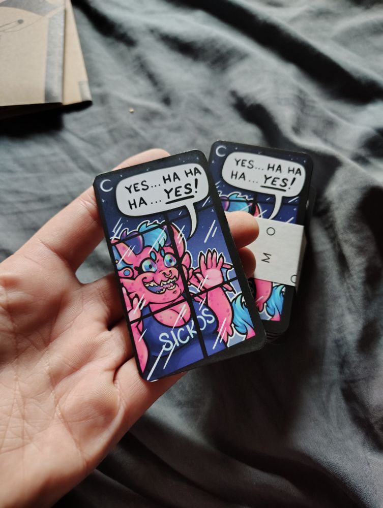 N holding a business card where it's the Fuchsia sickos drawing on one side