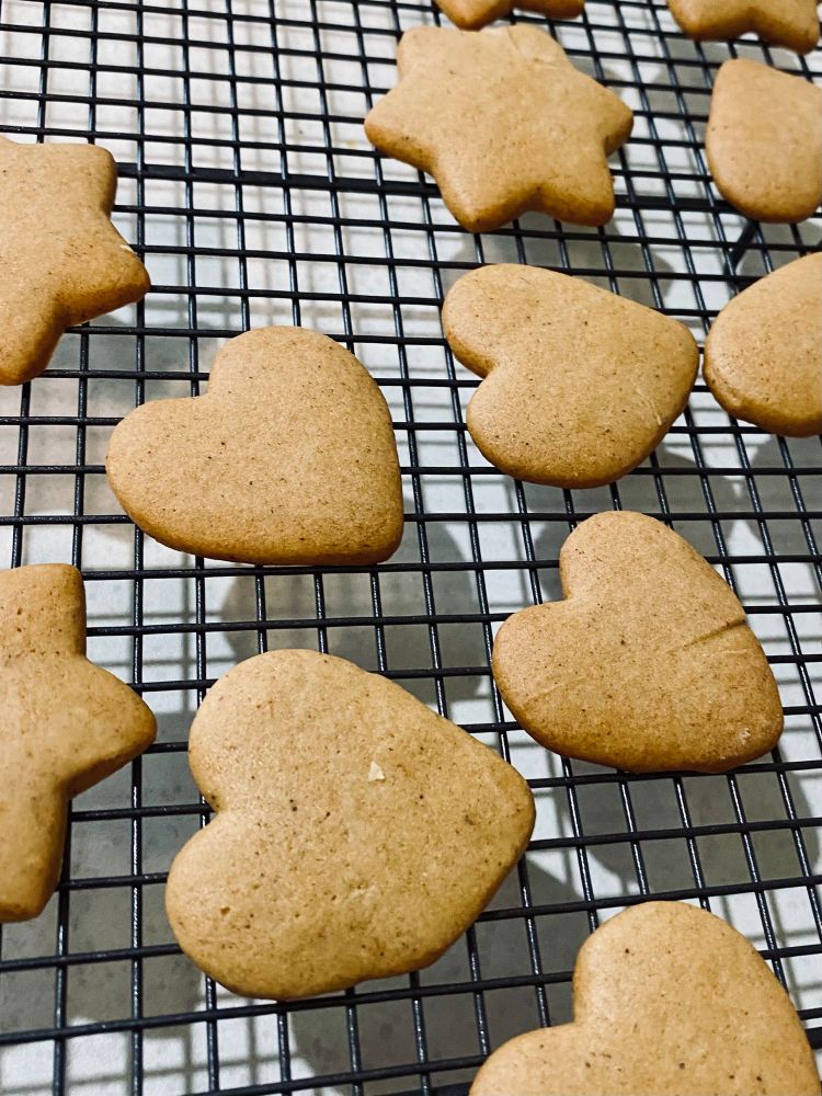 Cooling rack with freshly baked honey biscuits cut in heart shapes.