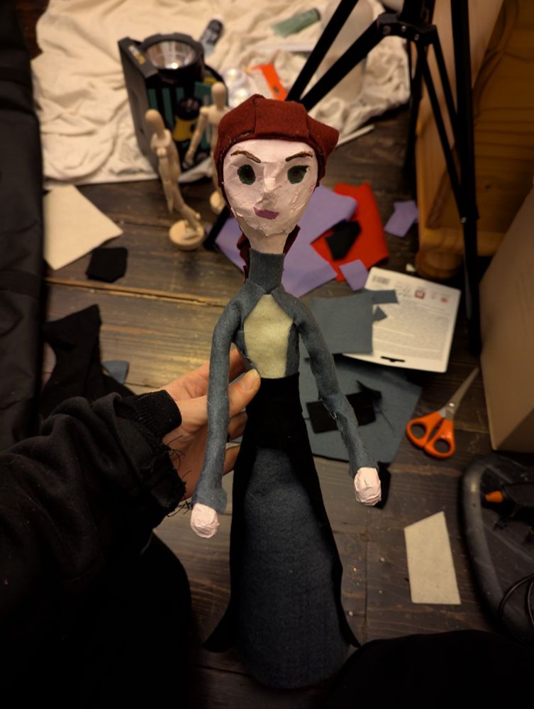A newly-made puppet with art materials in the background. 