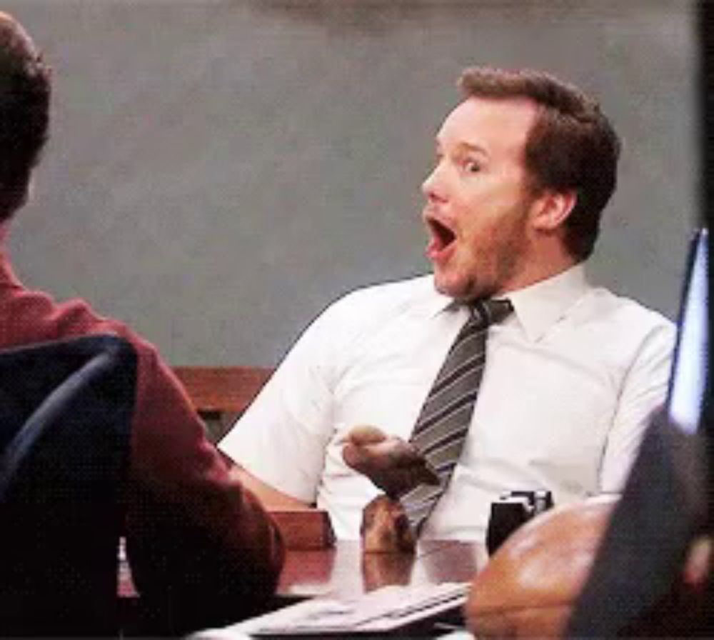 a man in a white shirt and tie sitting at a table with his mouth open