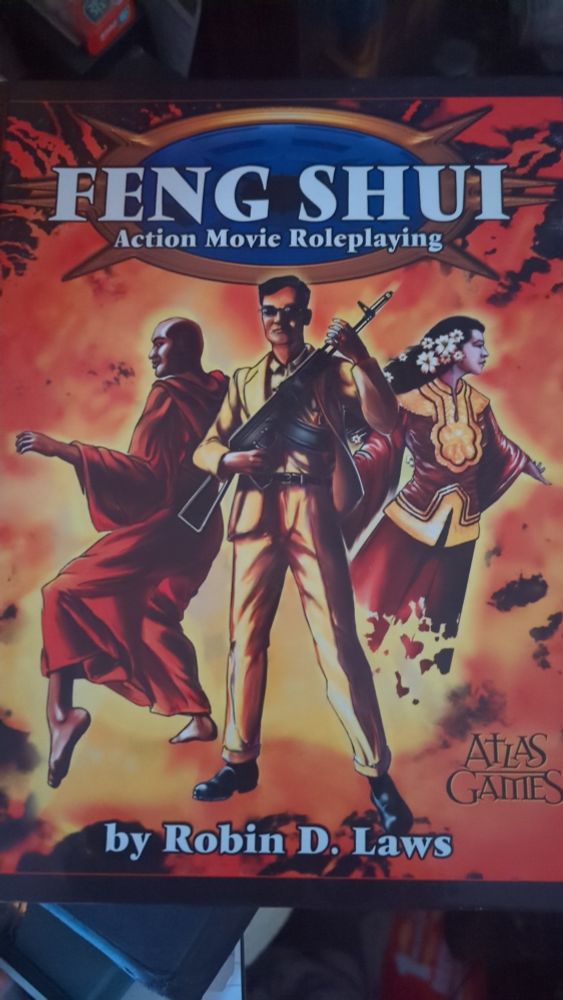 Front cover of Feng Shui Action Movies Roleplaying.
Three figures pose in front of the colours of an explosion.
A bald monk stands ready to fight, a suited gangster in sunglasses holds a machine gun, a female ghost in traditional dress states off to the side.