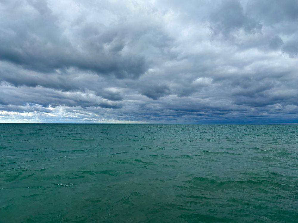 Deep green lake surface underneath a sky heavy with blue-grey clouds.