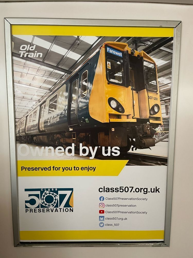 Photo of a poster advertising the C507PS’s old train. A large picture of shiny but old 507001 with text underneath “Owned by us. Preserved for you to enjoy”. The society logo appears with our many social media handles.