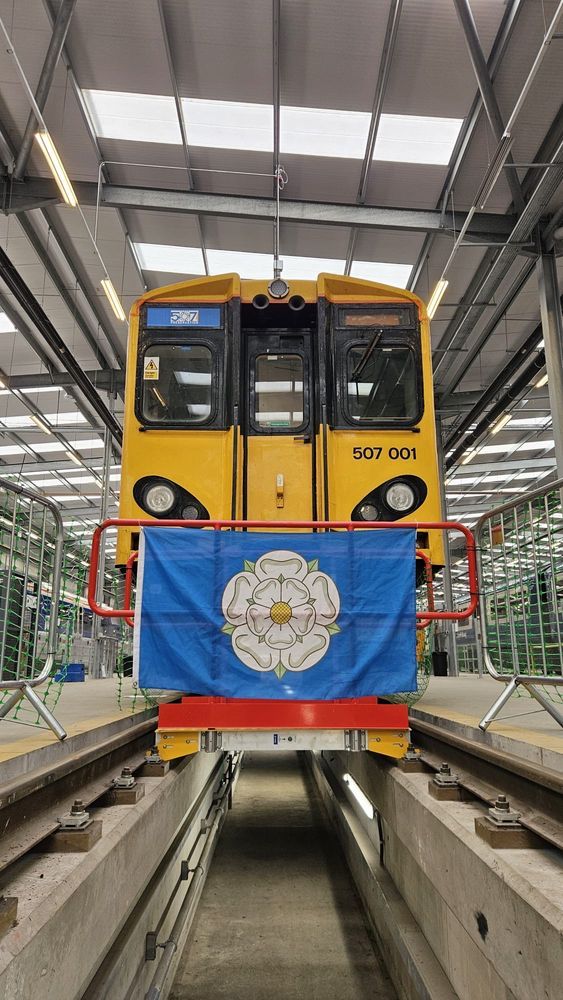 507001 in the V Shop at Derby with a Yorkshire flag hung in front of it 