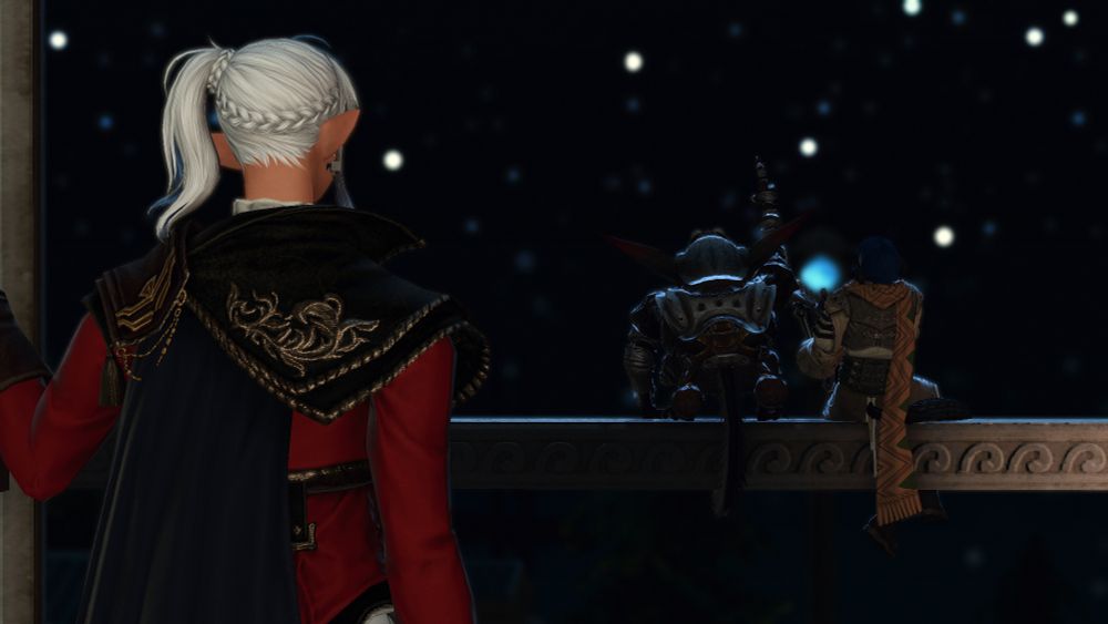A grown Alisaie stands at the left corner of the frame, looking out at Ga Bu and Ophelia, a Xaela Au Ra, sitting on the railing of the Leveilleur estate's balcony. The two outside are looking upwards at the star filled sky, with Ga Bu pointing out stars he recognizes while Ophelia strums away on a harp. Ophelia's hair is back to its natural dark blue, and they're wearing a light brown outfit with a long orange scarf. Alisaie is dressed in a red bliaud with a black cape and pauldrons, with a hand holding one half of the door she's looking out open. A light shines to the right side from out of sight, lighting up Ophelia slightly—though its source is obscured.