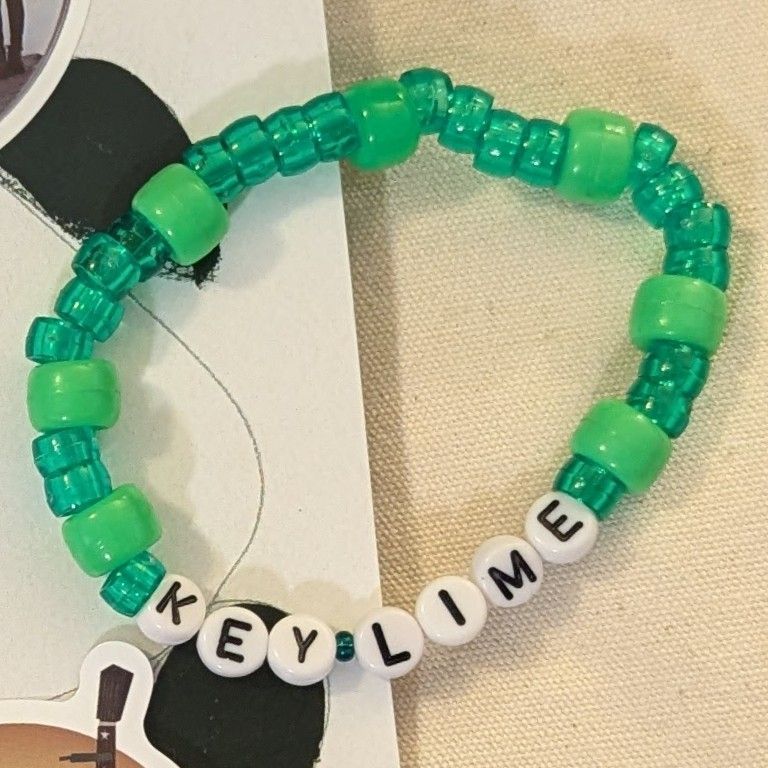 A friendship bracelet made of translucent, dark, key lime green beads and opaque key lime green beads, with "Key Lime" on white letter beads with black text.