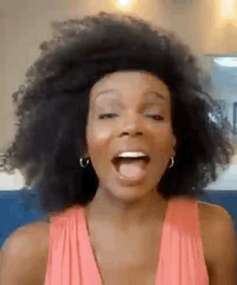 a woman with a big afro is making a funny face .