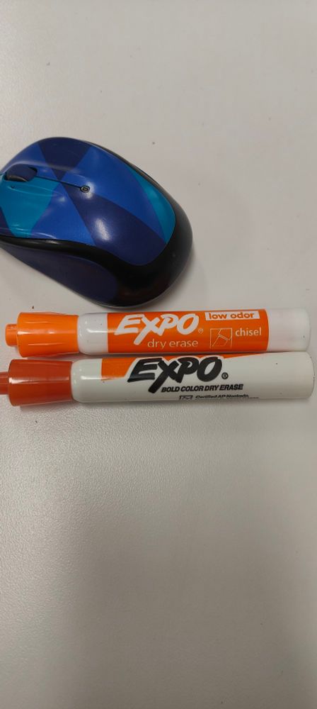 Two orange Expo dry erase markers. One newer on top that is low odor, and one older on the bottom that smells so bad omg 