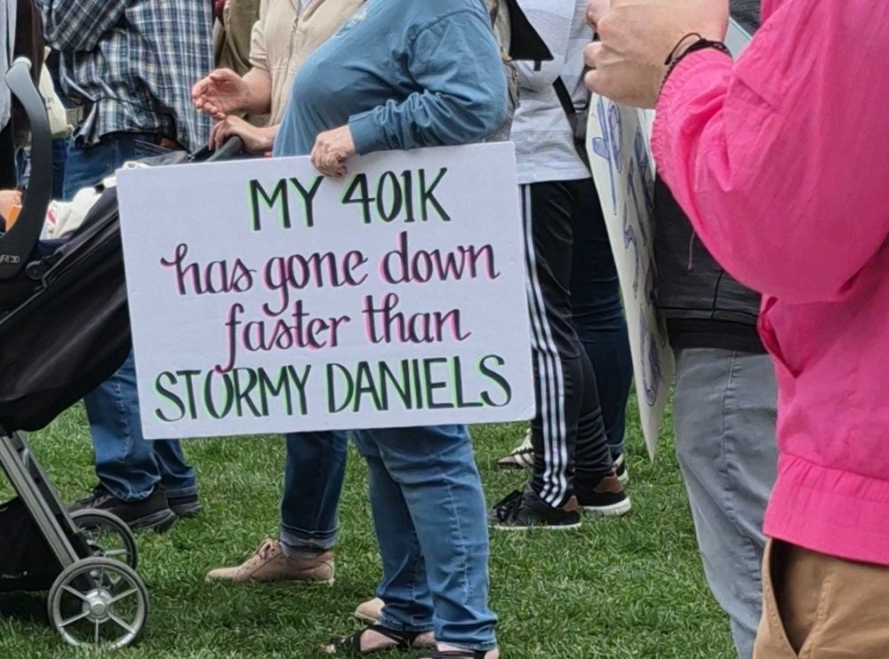 Hands Off protest sign that reads: My 401K has gone down faster than Stormy Daniels