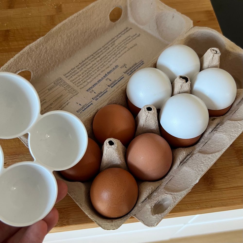 An egg carton and two plastic egg carriers for a fridge that have a neatly fitting hole in the middle so they can be placed atop the eggs still in the carton, so you can just flip the whole thing upside down.