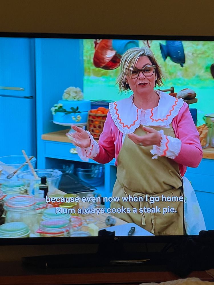 A contestant on The Great British Bake-Off wearing an oversized collar and cuffs (???)