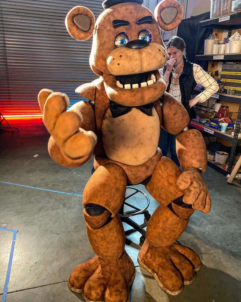 A behind the scene image from the Five Nights at Freddy's movie. Freddy Fazbear is sitting on a chair. 