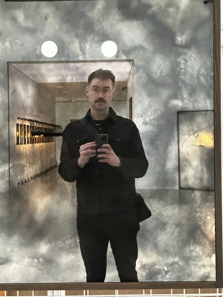 a photo of me standing in front of a reflective piece of art in the MUMOK museum. I’m wearing all black and i’m holding my phone.