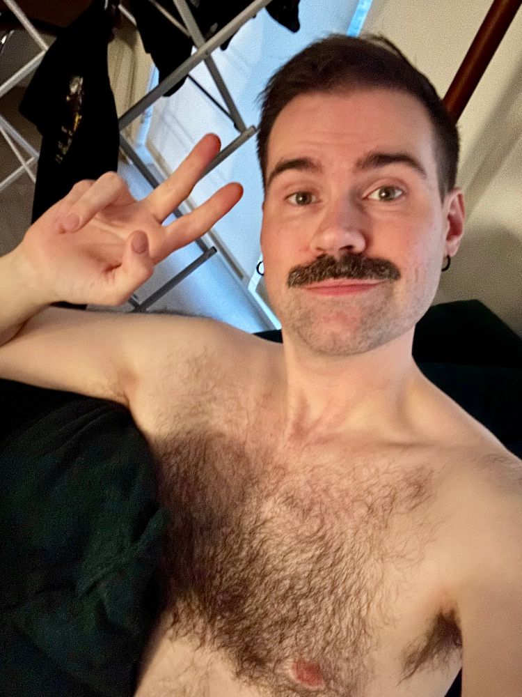 a photo of me sitting on a green sofa with my shirt off. 