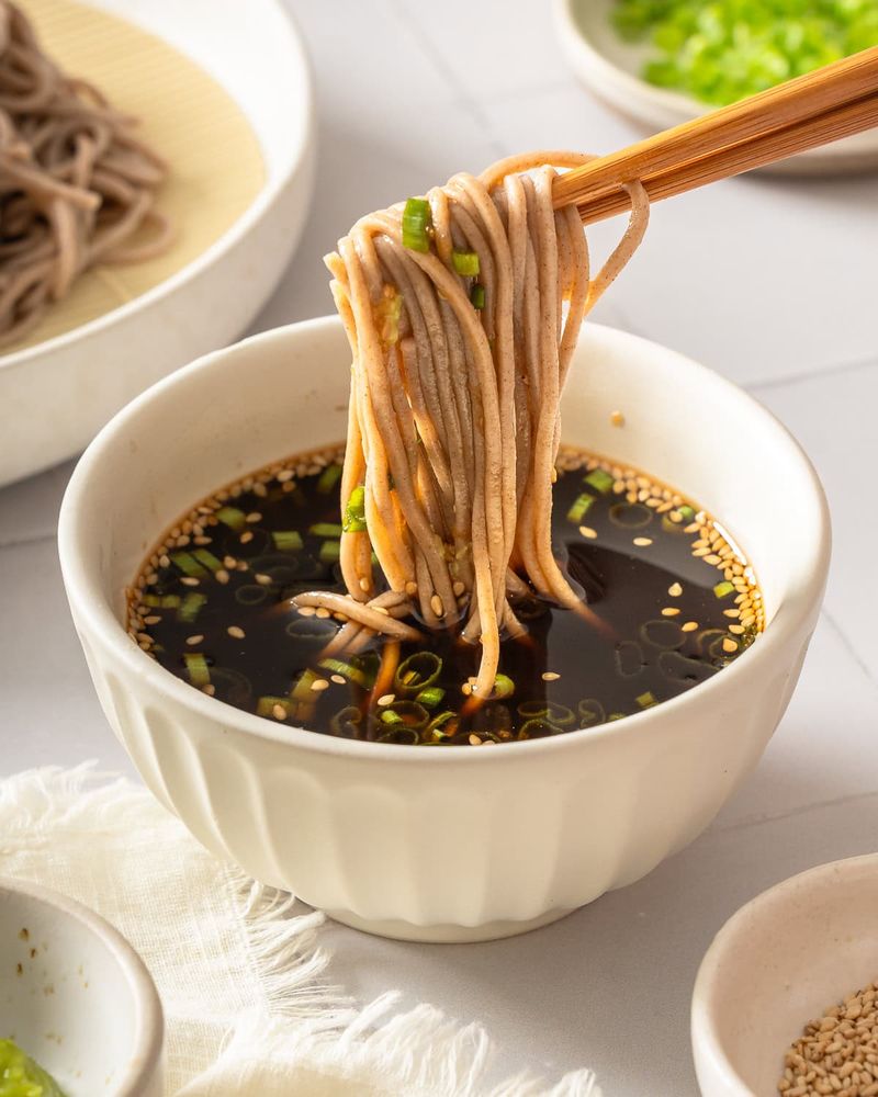 cold soba noodles being dipped into tsuyu sauce with chopsticks