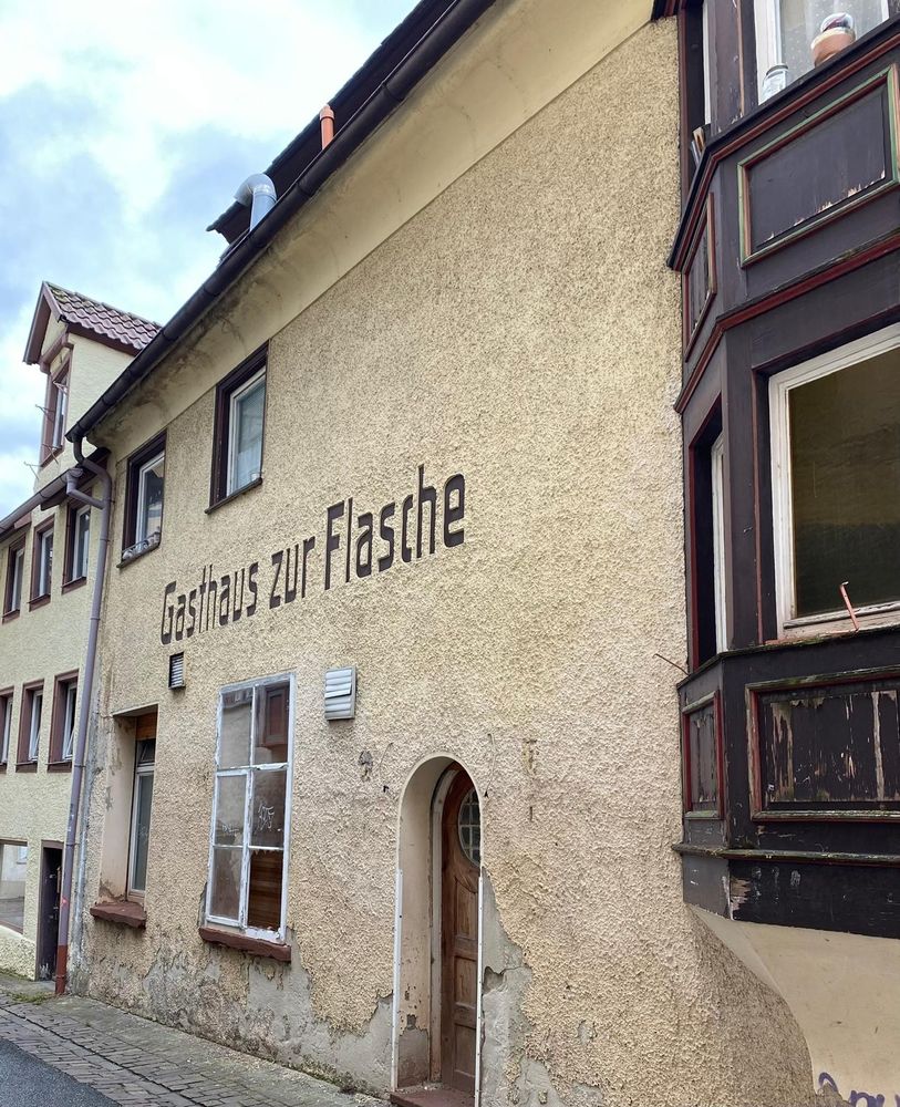Heruntergekommenes, historisches,  leer stehendes, beige verputztes "Gasthaus zur Flasche".
