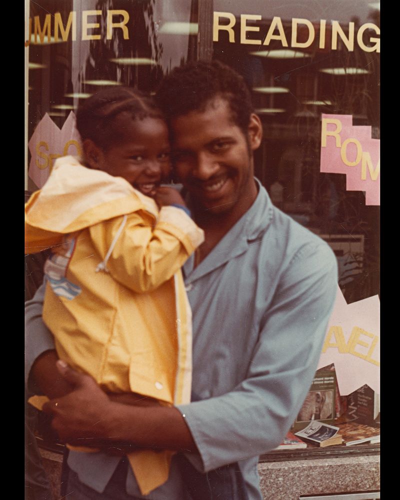A father holds his toddler daughter in his arms - both are smiling.