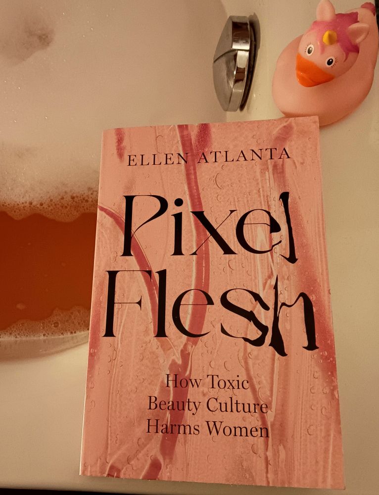 Buch "Pixel Flesh" von Ellen Atlanta auf Badewannenrand mit pinker Einhornente und rosa Badewasser.