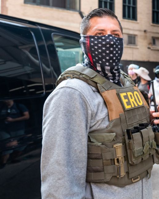 ERO Chicago agent in gray hoodie and black and white American flag gaiter (with red stripe for firefighters)