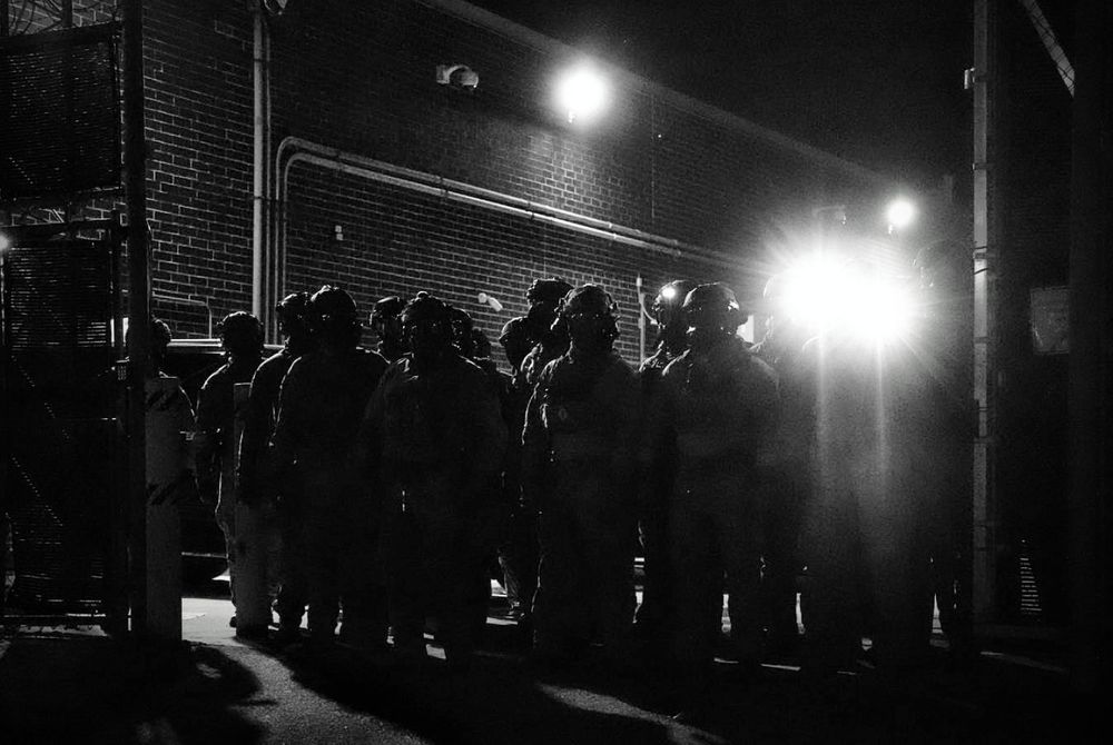 Ice agents in gas masks in dark driveway