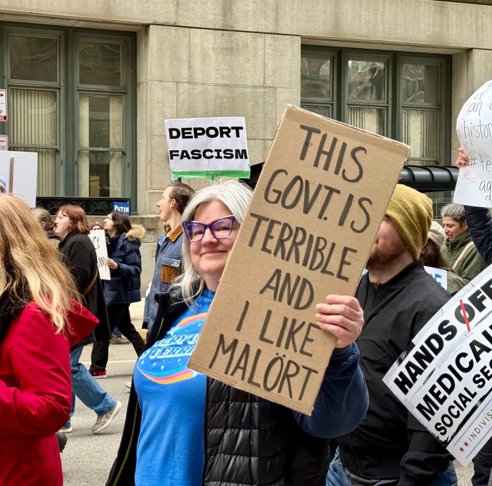 Woman holding a sign “this govt is terrible and I like Malört”